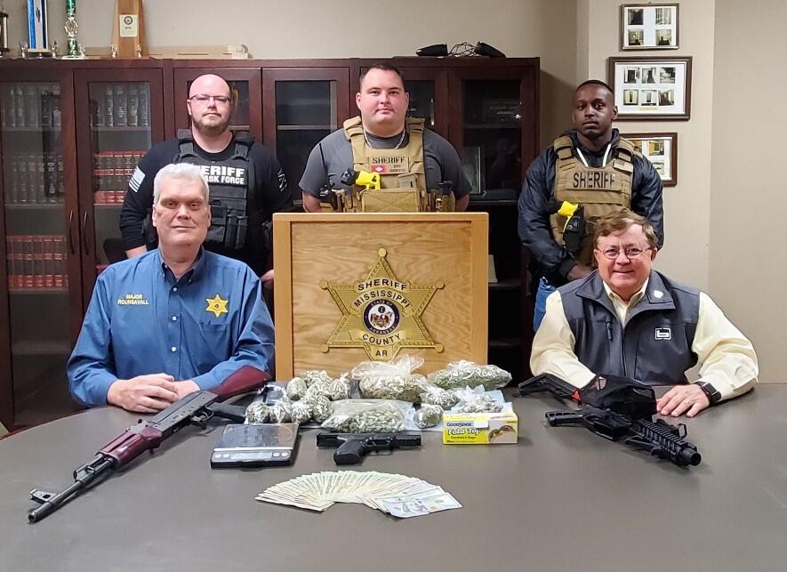 Image of officers with seized drugs and guns.