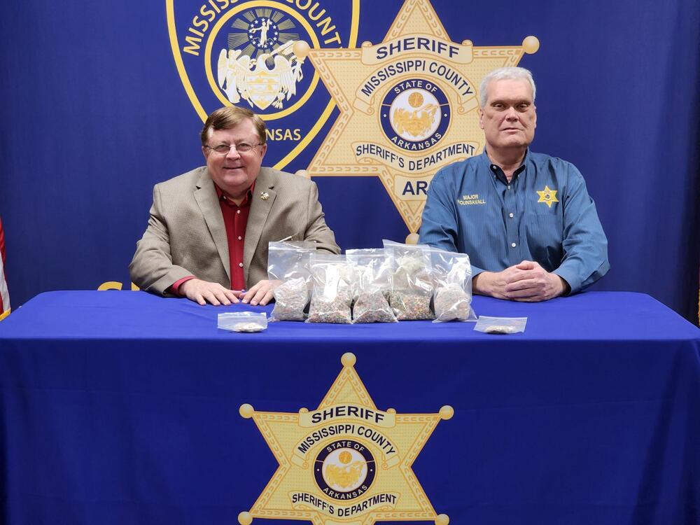 Sheriff Cook and Chief Deputy Robb Rounsavall sitting at table with drugs.