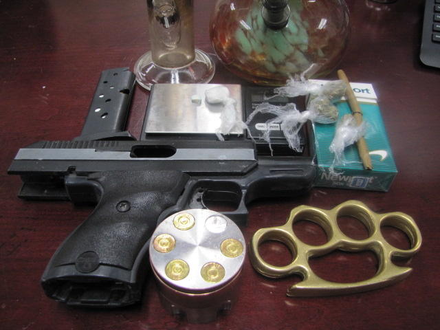 Drugs and gun displayed on table.