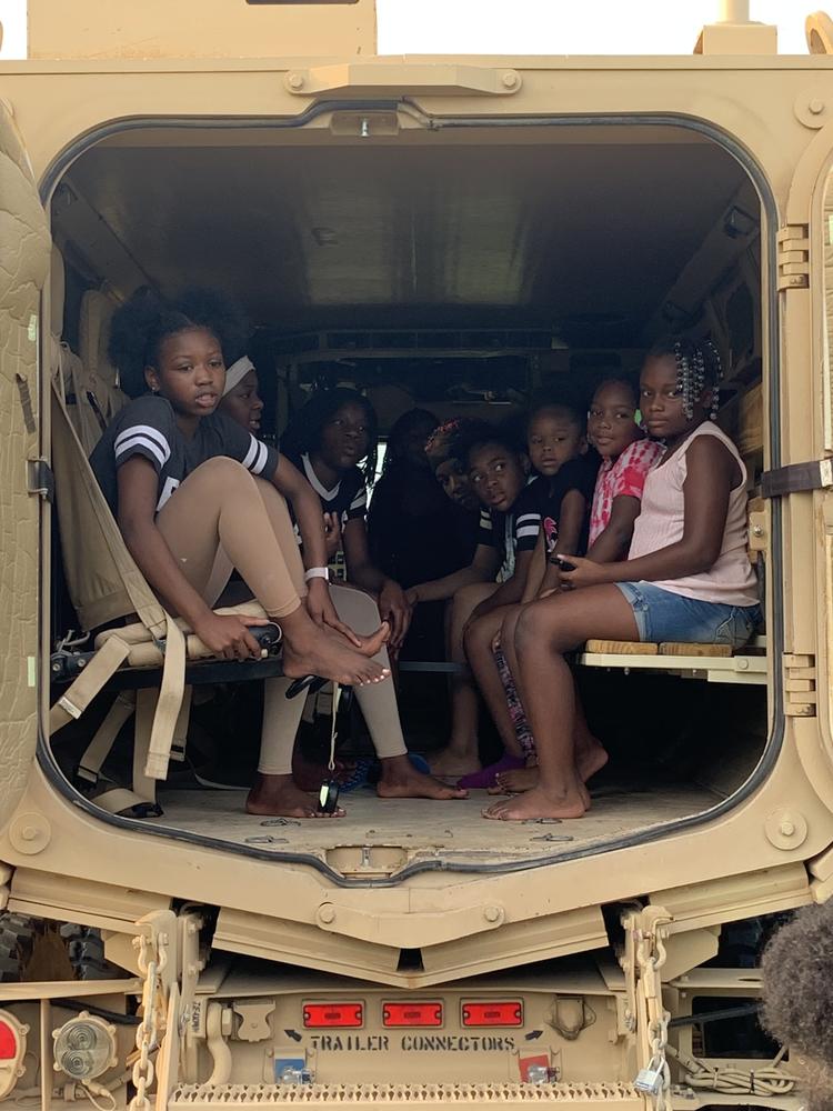 Image of children sitting in rear of armored vehicle. 